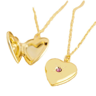 Gold heart-shaped locket with a pink gemstone on a white background