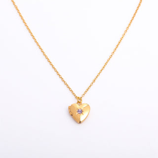 Gold heart-shaped necklace with a purple gemstone on a white background