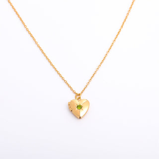 Gold heart-shaped necklace with a green gemstone on a white background