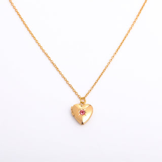 Gold heart-shaped necklace with a pink gemstone on a white background
