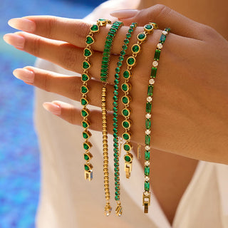 Gold tennis bracelet with emerald green bezel stones