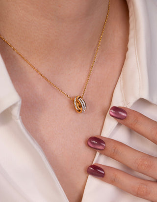Gold necklace with a circular pendant on a person wearing a white shirt.
