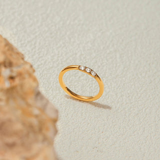 Gold ring with small diamonds on a textured beige background