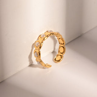 Gold ring with embedded pearls on a light beige background