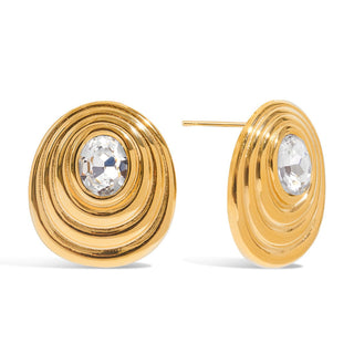 Gold hoop earrings with clear gemstones on a white background Bold gold earrings with clear faceted oval stone

