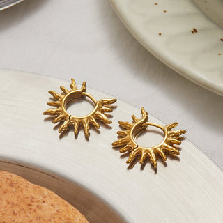 Close-up of a hand wearing a gold earrings, held by another person.