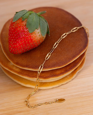 Gold chain bracelet on pancakes with a strawberry