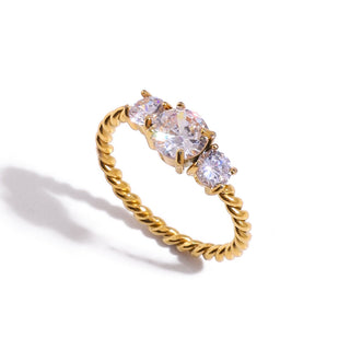 Gold ring with three clear gemstones on a white background