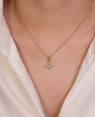 Gold necklace with a delicate pendant on a person wearing a white blouse.
