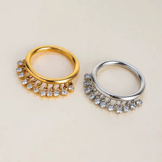Gold and silver rings with dangling crystals on a beige background