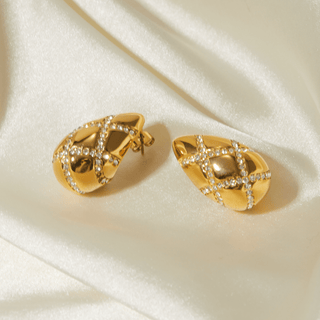 Gold earrings with diamond accents on a white fabric background