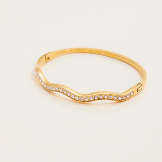 Gold bracelet with small crystals on a light beige background