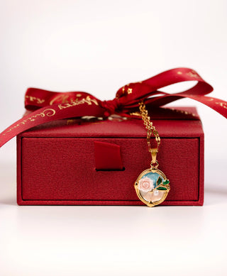 Gold necklace with a decorative pendant on a red box with a bow