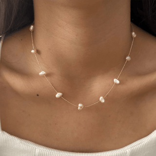 Pearl necklace on a person's neck with a neutral background