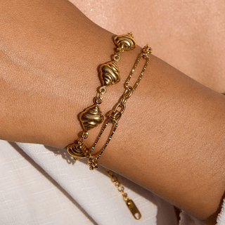 Gold bracelet on a wrist with a neutral background