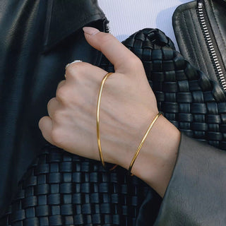 Hand wearing a gold bracelet with a textured black background