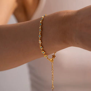 Gold bracelet with blue stones on a wrist against a neutral background