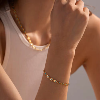 Close-up of a person wearing a gold bracelet with blue stones on a neutral background