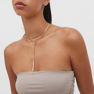 Woman wearing a gold necklace with a plain background