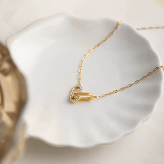 Gold necklace with a pendant on a white dish