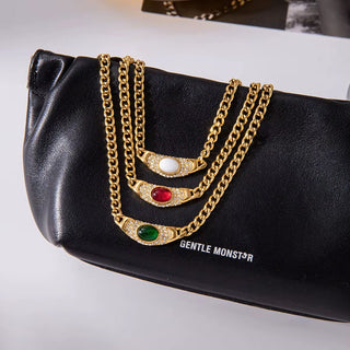 Black clutch with gold chains featuring gemstones on a white background