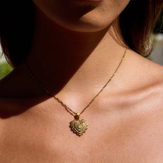 Gold heart-shaped necklace on a person's neck with a blurred background