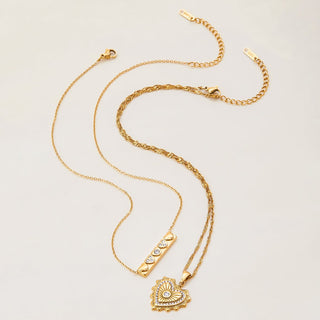 Gold necklace with heart-shaped pendant on a light beige background