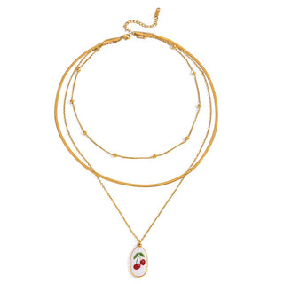 Gold necklace with a cherry pendant on a white background
