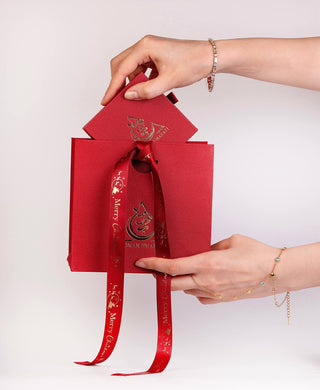 Red gift bag with a ribbon held by hands on a white background