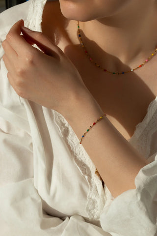Close-up of a person wearing colorful beaded jewelry with a white garment.