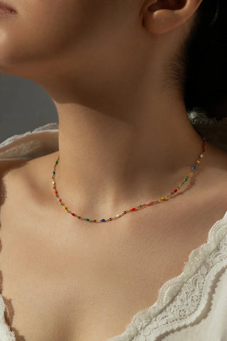 Close-up of a person wearing a colorful beaded necklace with a neutral background