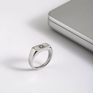 Silver ring with engraved design on a light gray surface