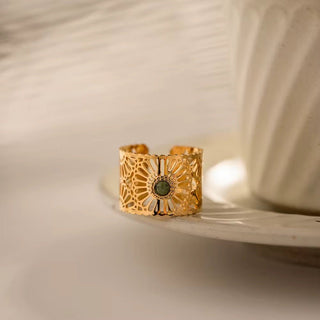 Gold ring with intricate design on a white plate