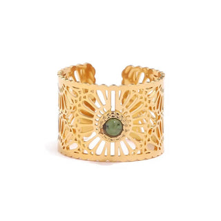 Gold cuff bracelet with a green gemstone on a white background