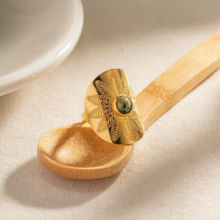 Wooden spoon with gold decorative lid on a light background