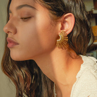 Close-up of a woman wearing a gold earring with a blurred background
