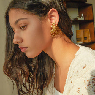 Woman wearing gold earrings with a blurred indoor background