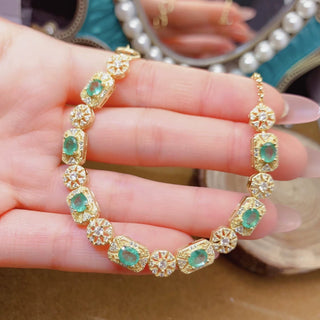 Gold bracelet with green zambian emerald gemstones on a hand