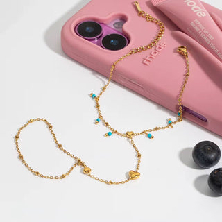 Gold chain necklace with heart-shaped pendants on a pink phone case with 'th mee' branding.