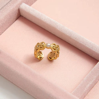 Gold ring with a pearl on a pink velvet surface